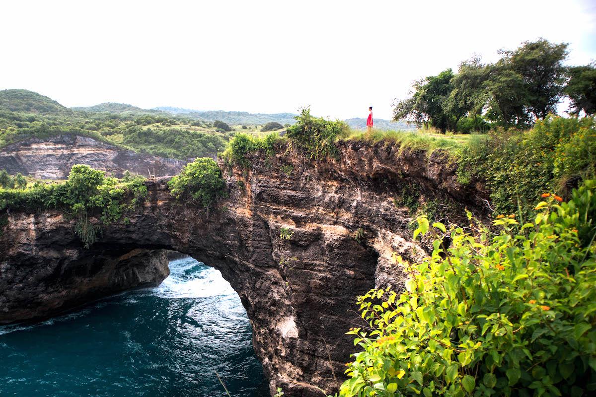 Girl sitting on the edge of the Broken Beach arch in Nusa Penida