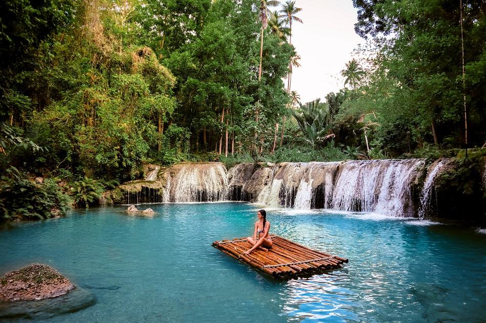 Girl on a bamboo raft at Cambugahay Falls, Siquijor