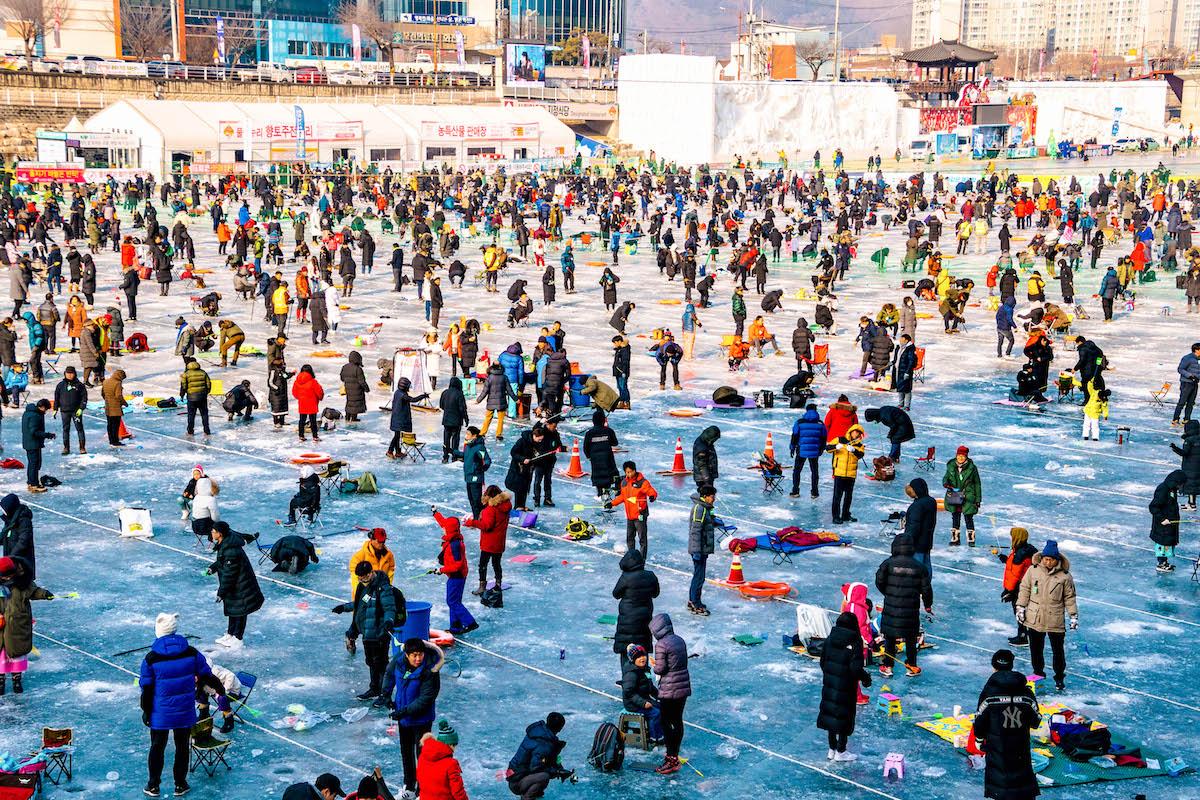 Hwacheon Sancheoneo Ice Festival in South Korea. People ice fishing in Korea in winter - things to do in Korea in Winter, winter destinations in Korea, winter activities in South Korea