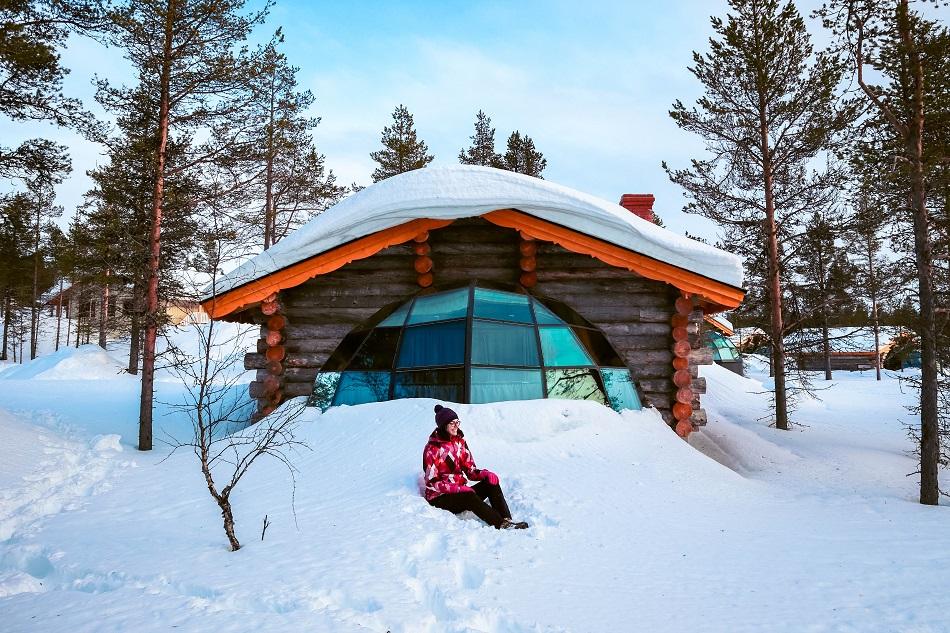 Aurelia Teslaru sitting in front of Kelo Glass Igloo at Kakslauttanen Arctic Resort Lapland during winter