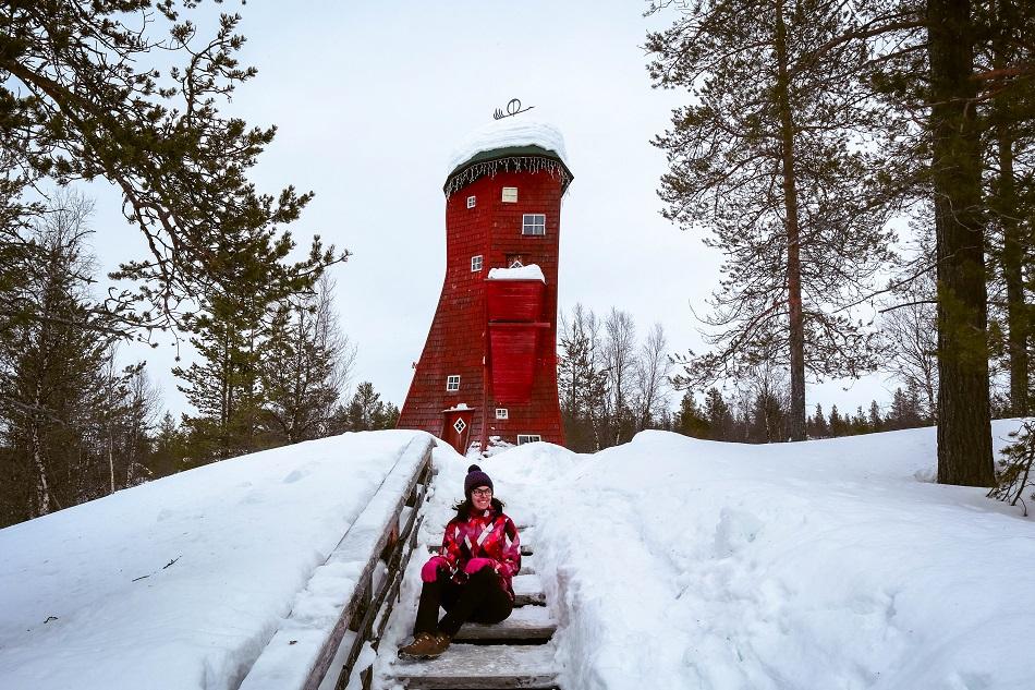 Girl sitting in front of a red elf tower at Kakslauttanen Arctic Resort, Lapland