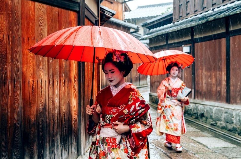 2 geishas with red umbrellas in Kyoto