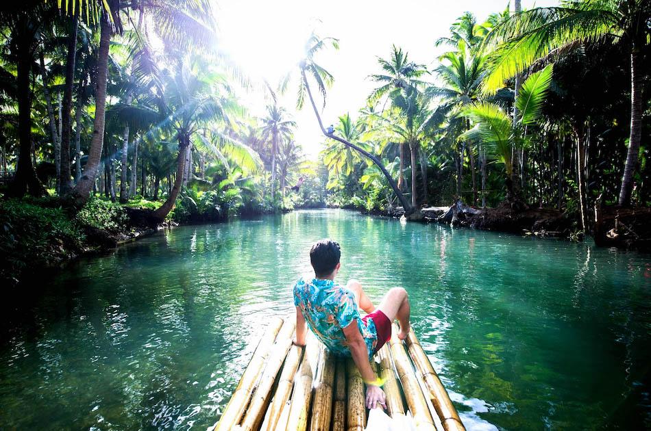 Man on a wooden raft at the Bent Palm Tree in Siargao.