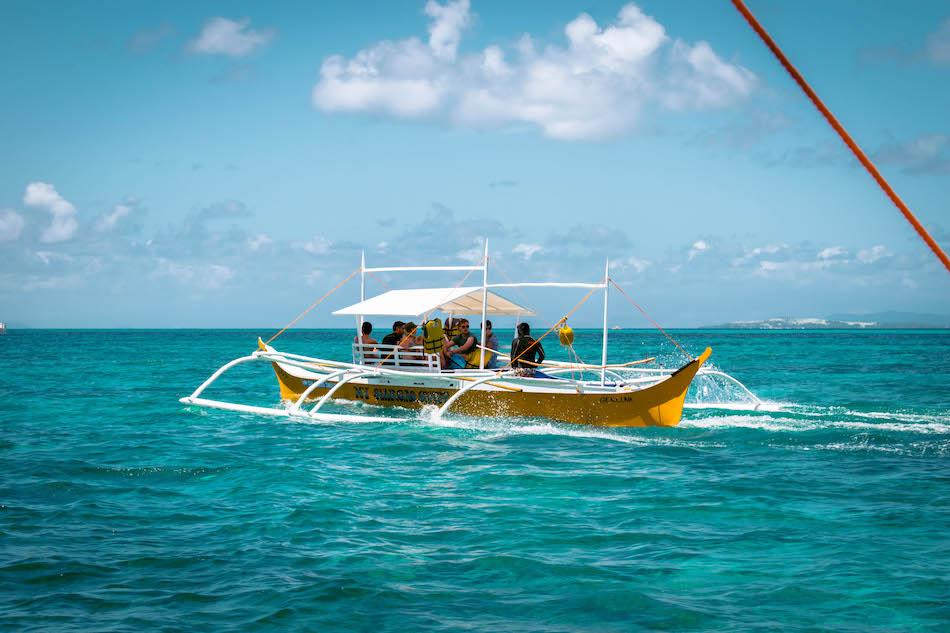 Island Hopping tour in Siargao. Local boat with tourists heading to Guyam Island, Naked Island and Daku Island