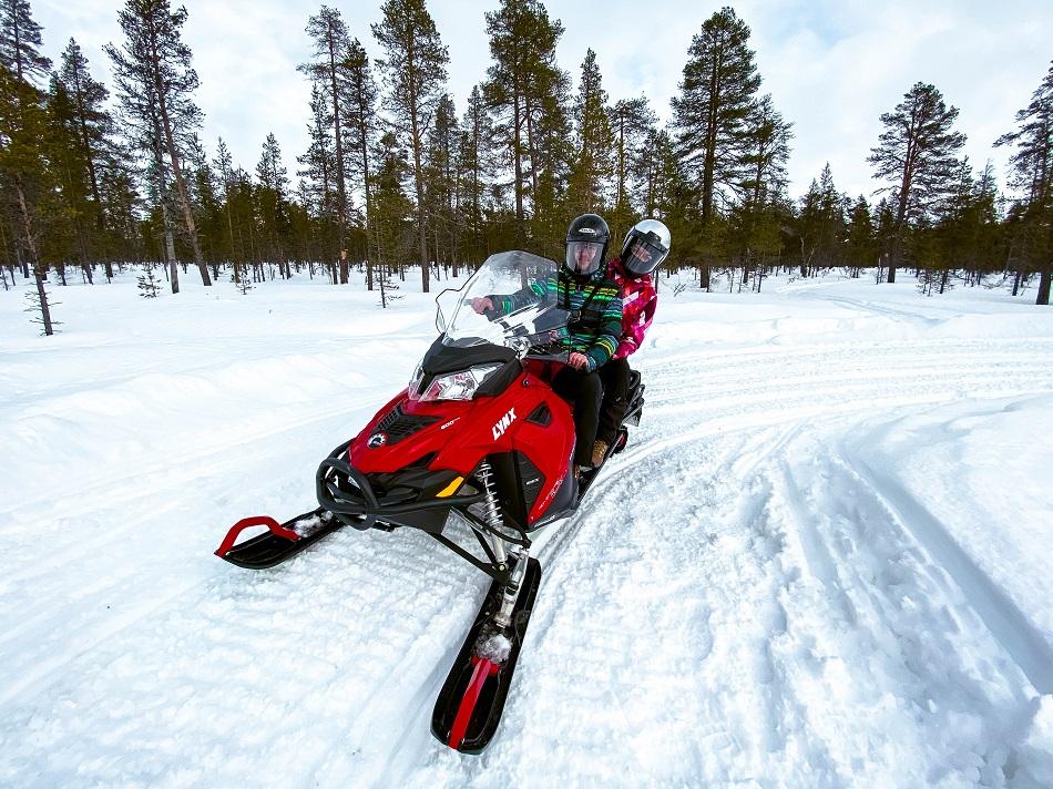 Aurelia Teslaru and Dan Moldovan on a red snowmobile inside the forest in Lapland, Finland