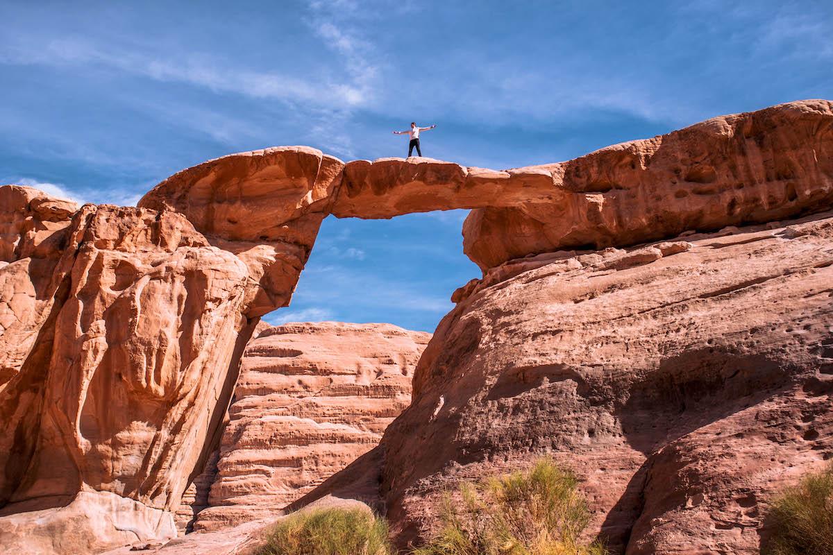 Man on top of an arch in Wadi Rum Desert
